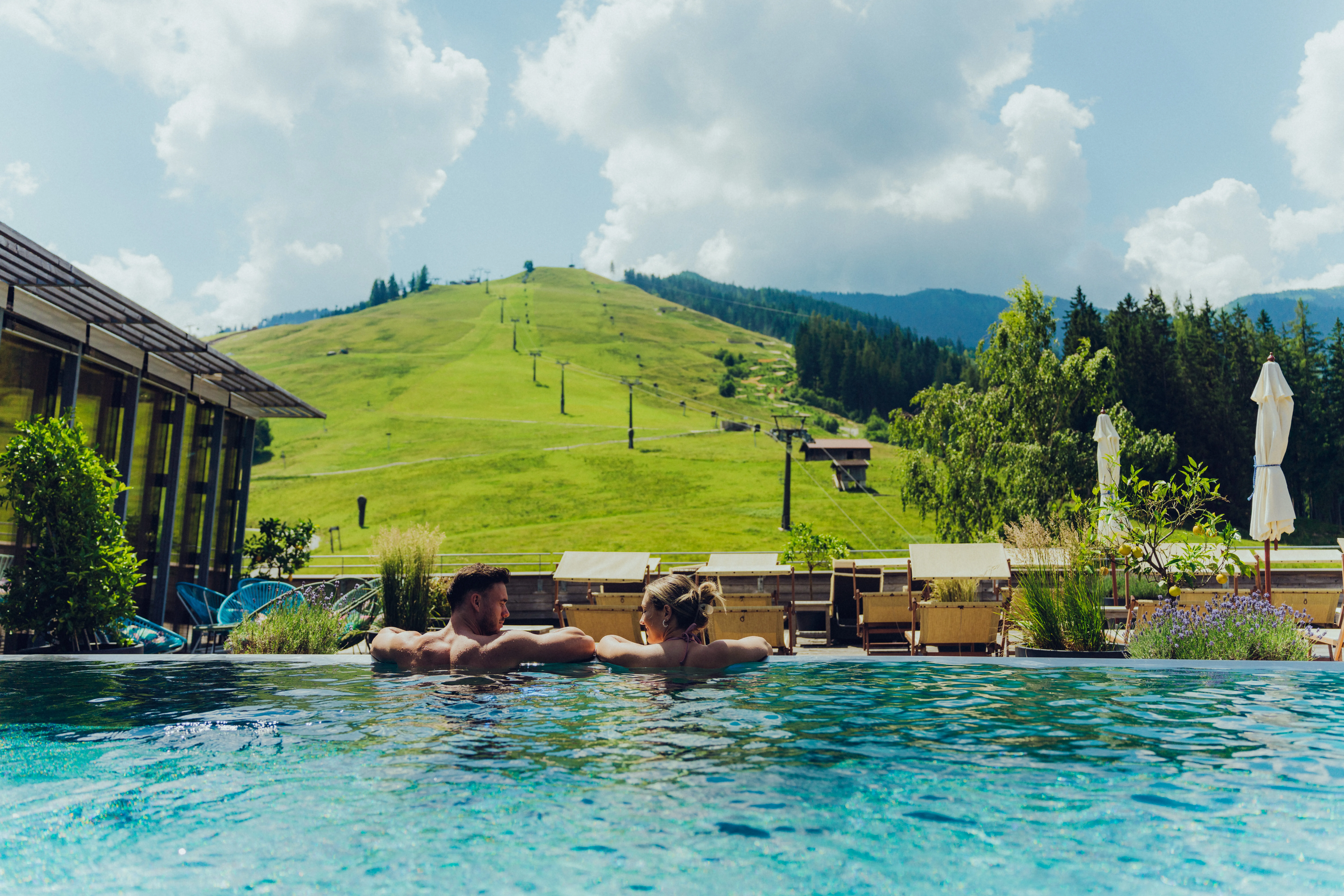Paar entspannend im Pool mit bergiger Landschaft im Hintergrund