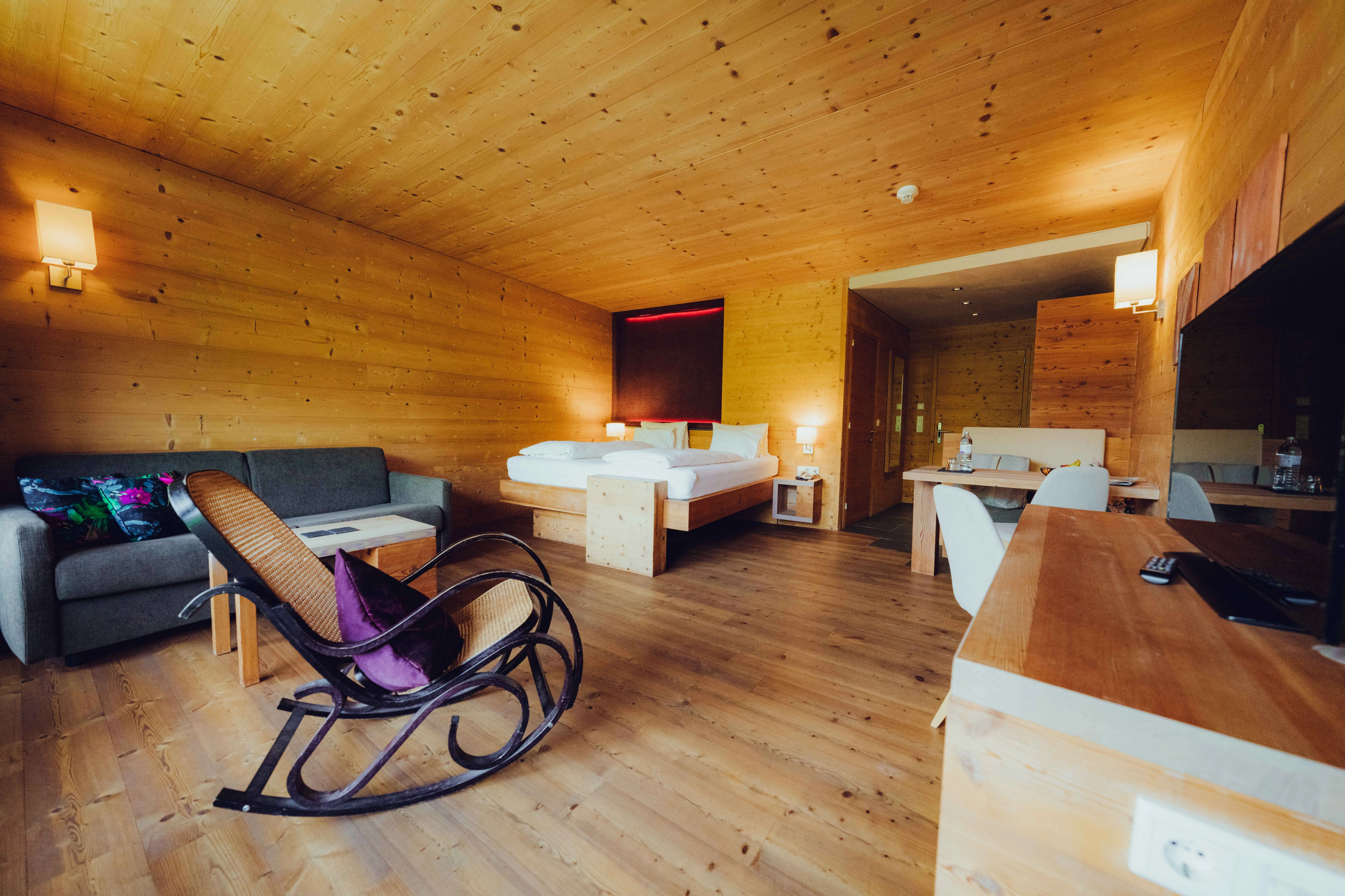 Helles Zimmer mit Holzvertäfelung, Bett, Sofa und Sessel.