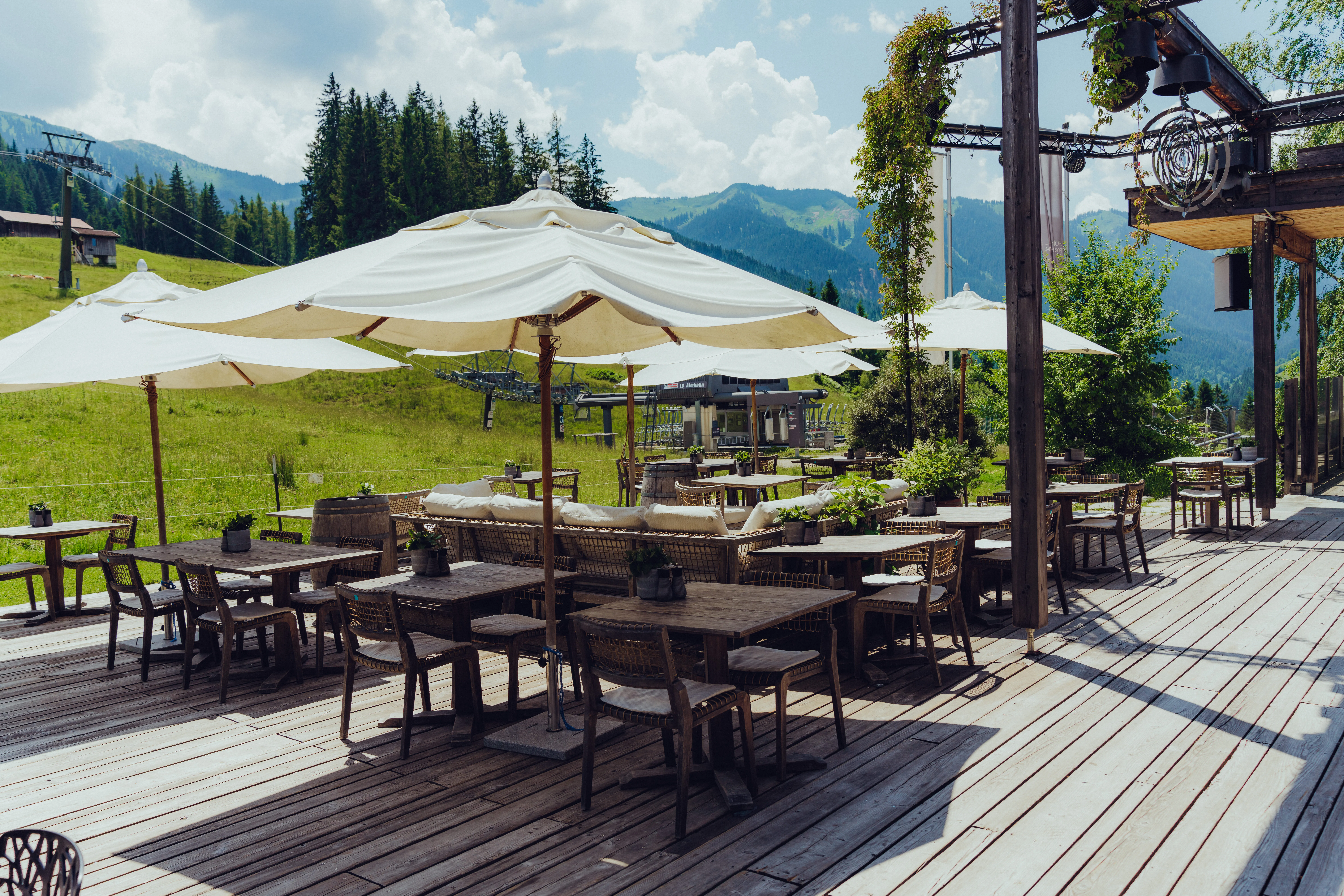 Terrasse mit Sonnenschirmen, Tischen und Stühlen in den Bergen