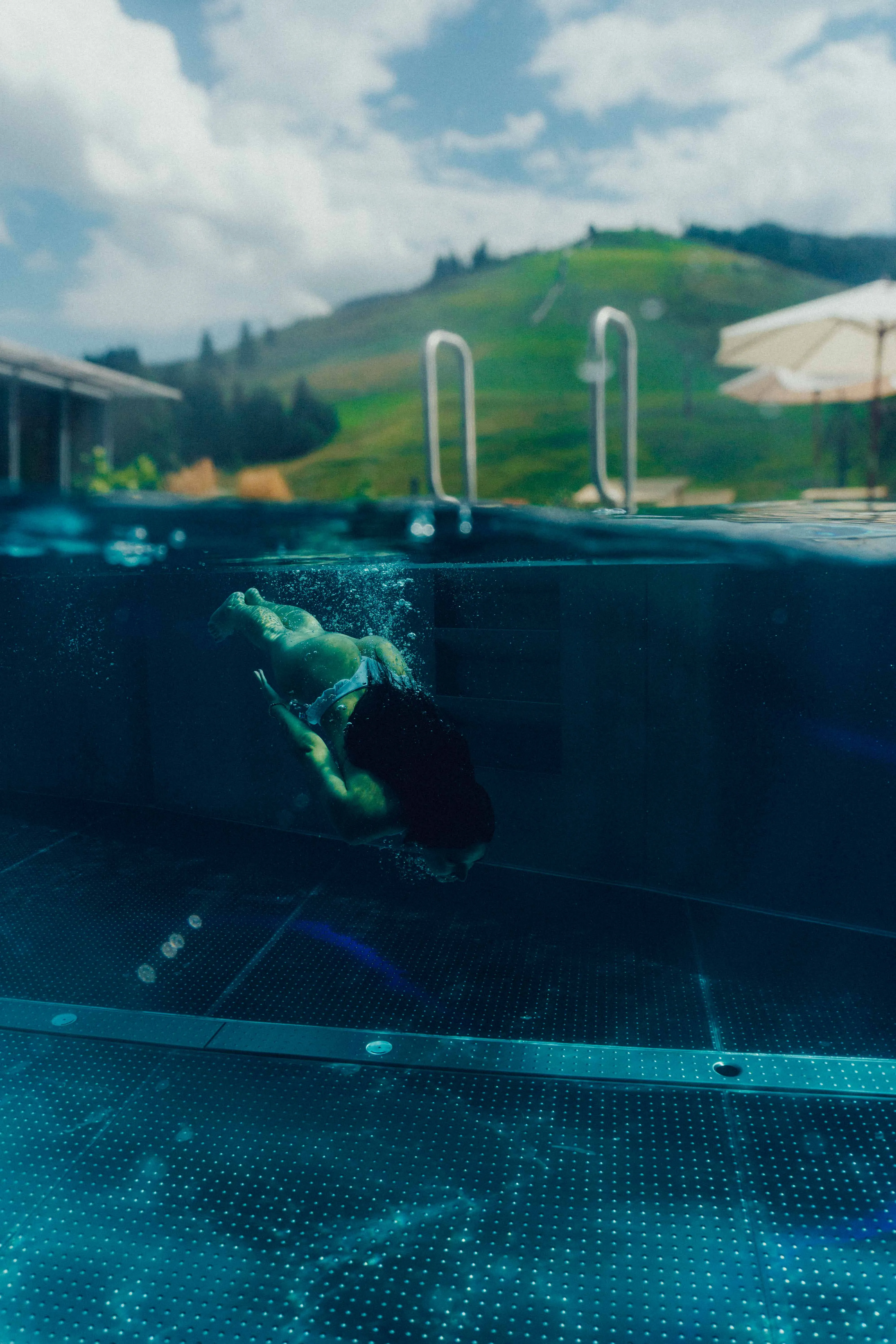 Person schwimmt im Pool mit Blick auf die Berge