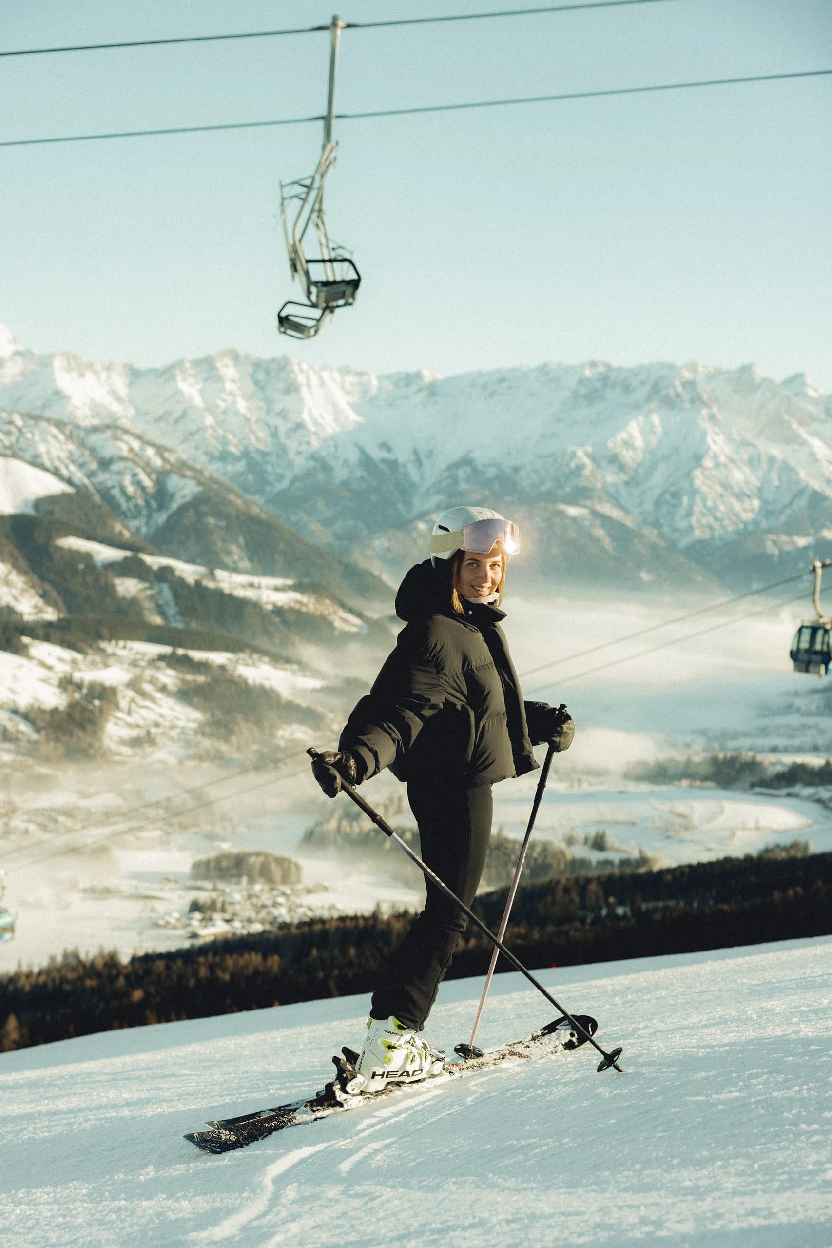 Skifahrer auf Piste mit Bergen und Seilbahn im Hintergrund