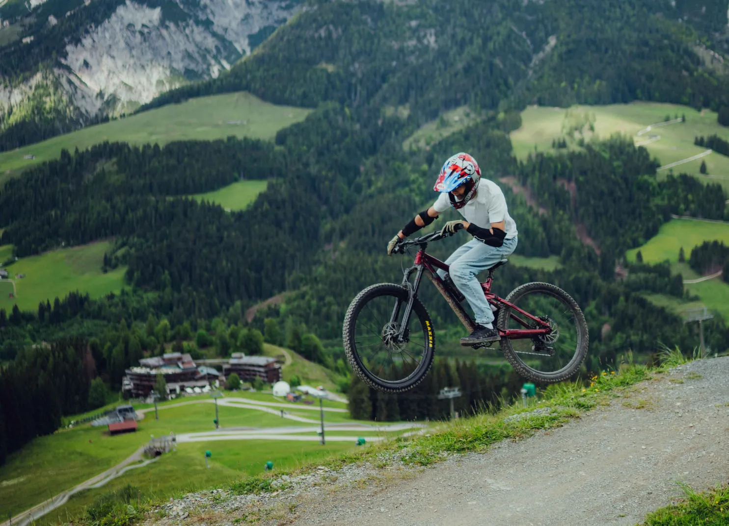 Fahrer springt mit Mountainbike über ein Gelände in den Alpen