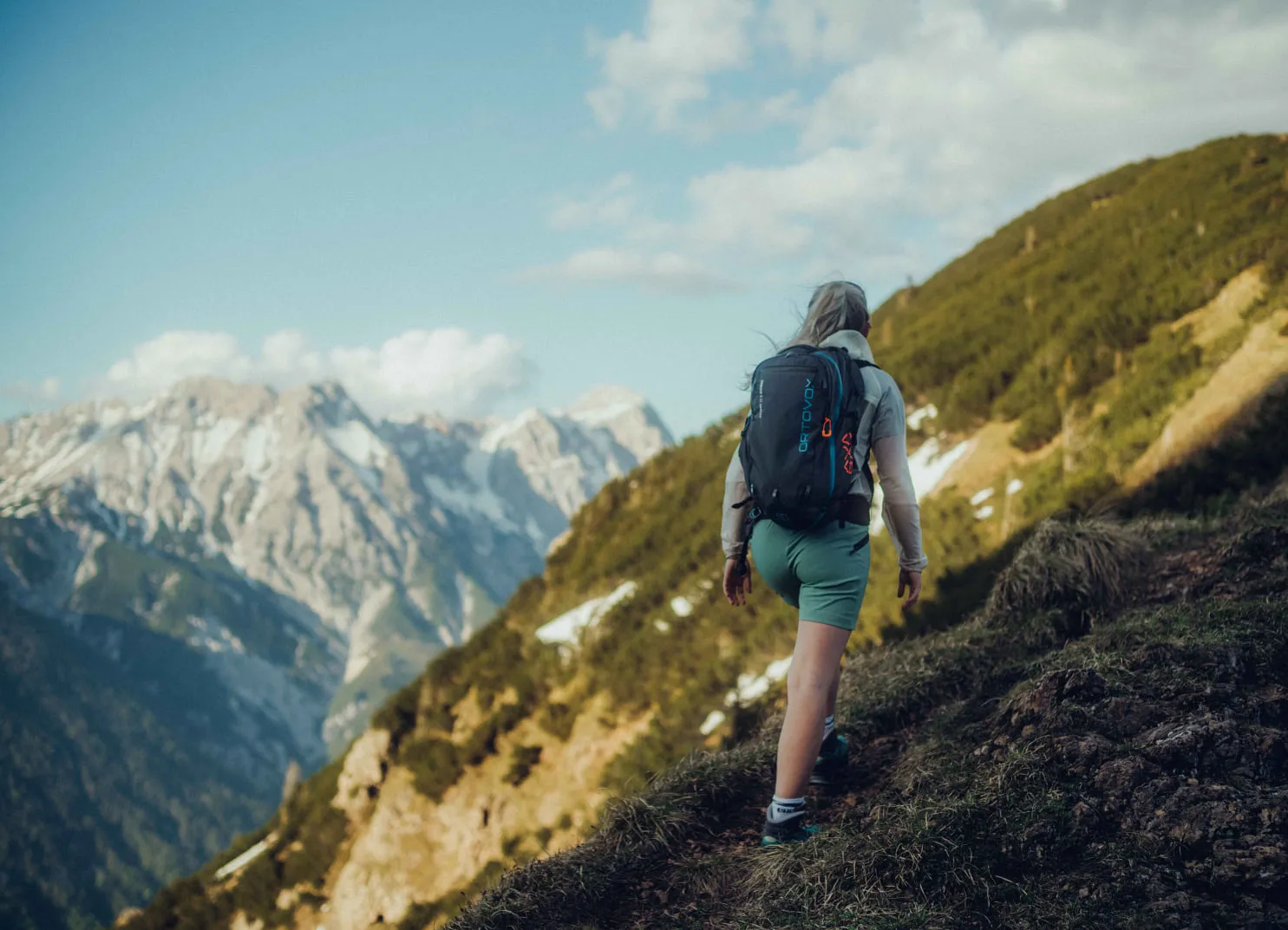 Eine Wanderin geht einen Bergweg entlang.