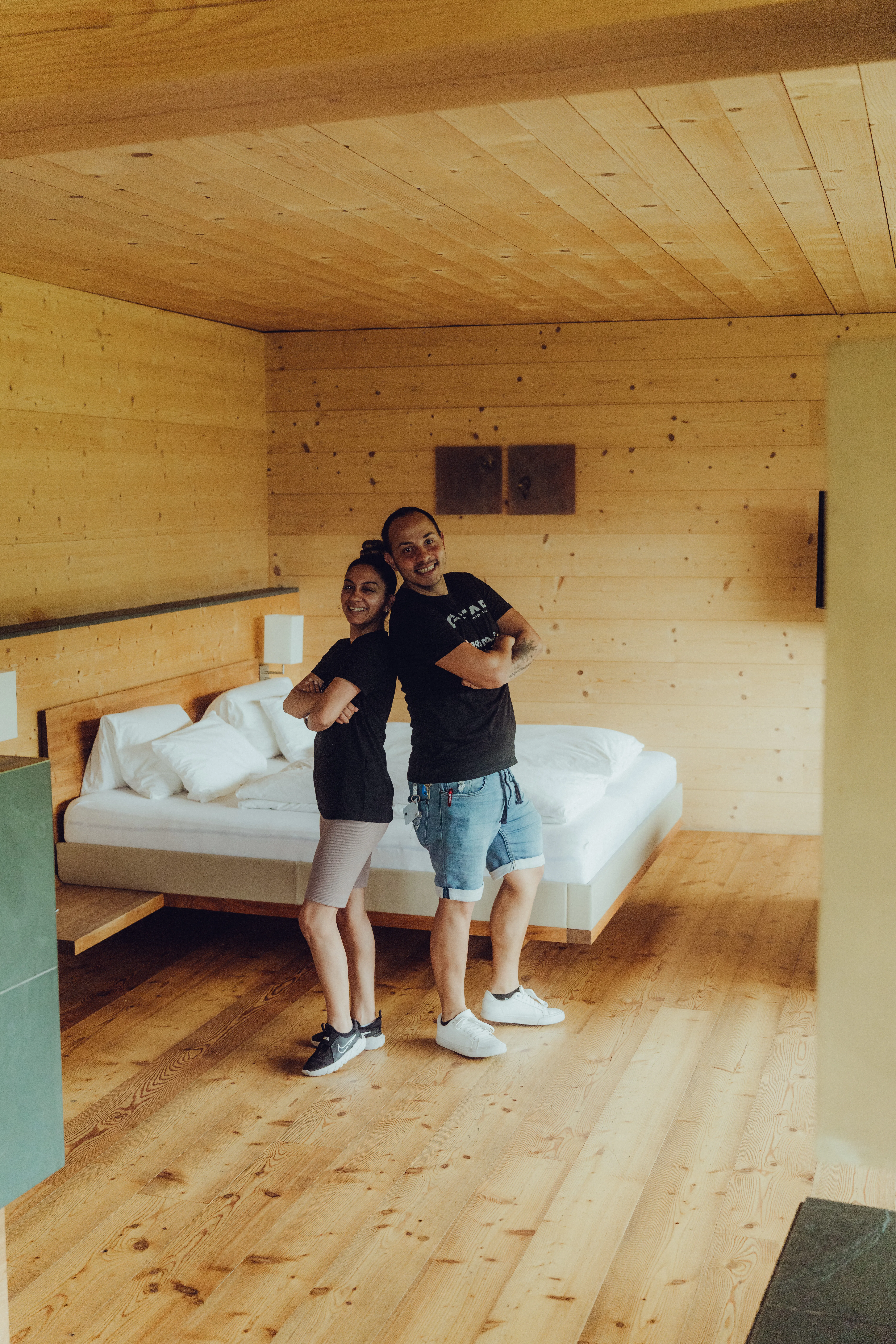 Zwei Personen posieren in einem Holzraum mit Bett